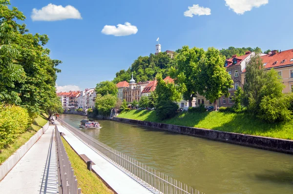 Barco en el río Liublianica y castillo elevándose por encima de la colina — Foto de Stock