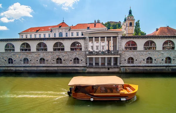 Barco en el río Liubliana y la iglesia de San Nicolás en el backgro — Foto de Stock