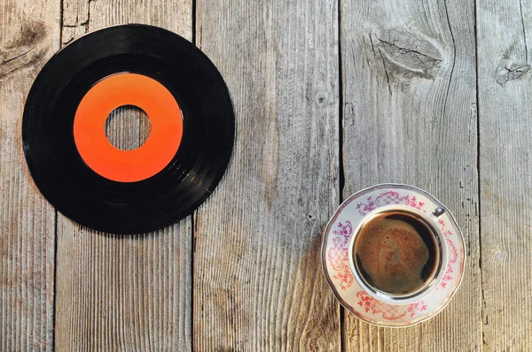 Старая виниловая пластинка и чашка кофе на деревянном столе — стоковое фото
