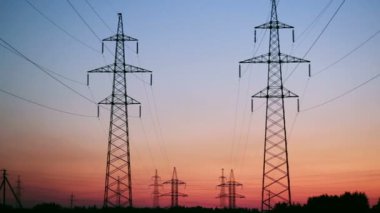Ufukta güneş doğarken uzanan yüksek gerilim hatları destekler