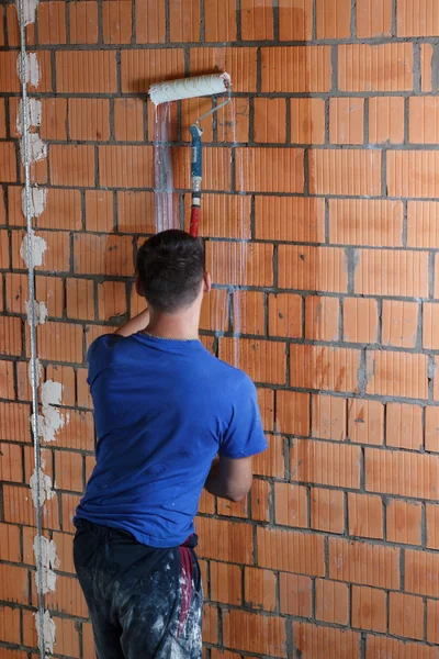 Trabajador pone en la imprimación de la pared con un rodillo Imagen De Stock