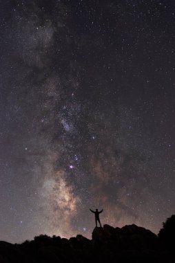 Samanyolu 'nun muhteşem manzarası. Küçük bir adam silueti ona bakıyor.