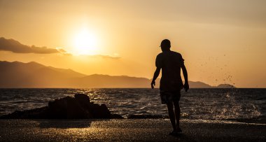 Adam ve güzel bir gün batımı sıçramasına dalgalar