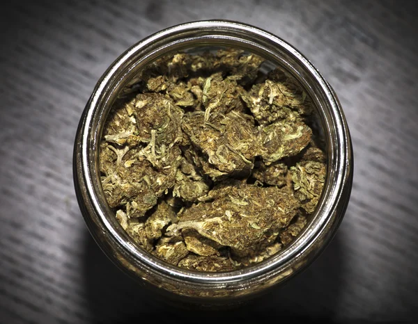 Jar of marijuana on wooden black table — Stock Photo, Image