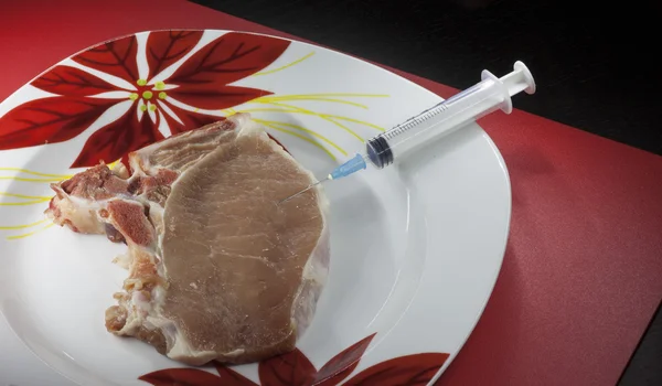 Concept genetically modified organism: syringe and meat — Stock Photo, Image