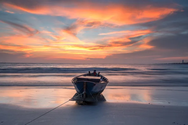 Рыбацкая лодка на пляже на закате — стоковое фото