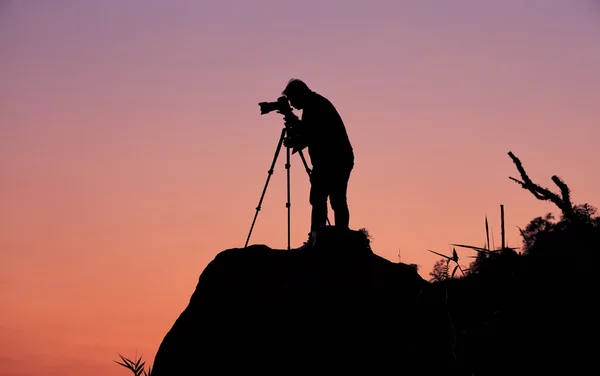 Силуэт фотографа, который снимает закат на горе — стоковое фото