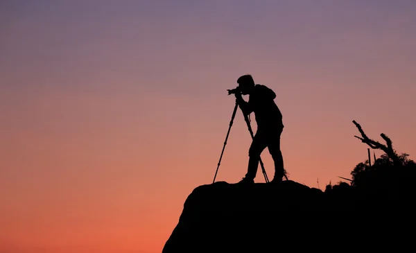 Silhouette of a photographer who shooting a sunset on the mounta — Stock Photo, Image