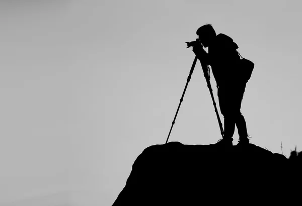 Silueta de un fotógrafo que dispara una puesta de sol en la montaña — Foto de Stock