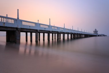 Güzel bir gündoğumu ile deniz üzerinde uzun beton köprü ,
