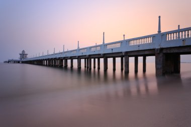 Güzel bir gündoğumu ile deniz üzerinde uzun beton köprü ,