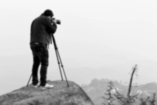 Fotógrafo desfocado atirando o pico da montanha em preto e — Fotografia de Stock