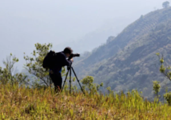 Fotógrafo desfocado atirando no pico da montanha — Fotografia de Stock