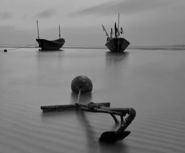 Balıkçı teknesi sahilde günbatımı siyah beyaz sırasında — Stok fotoğraf