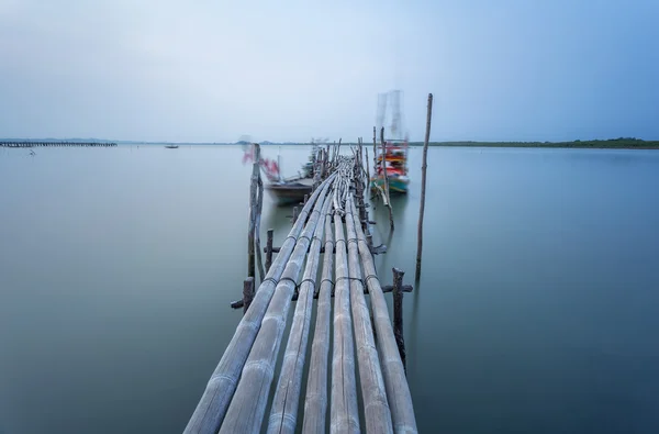 Бамбуковый мост и движущаяся рыбацкая лодка — стоковое фото