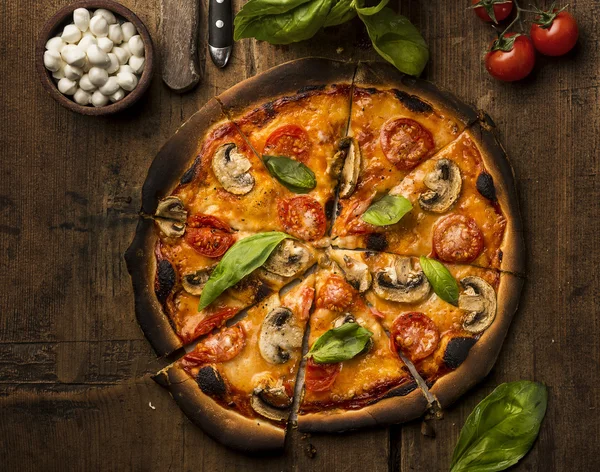 Pizza med mozzarellaost på ett träbord — Stockfoto