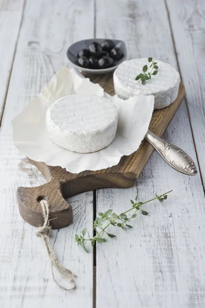Queso Brie con galletas y aceitunas en la mesa de madera blanca —  Fotos de Stock
