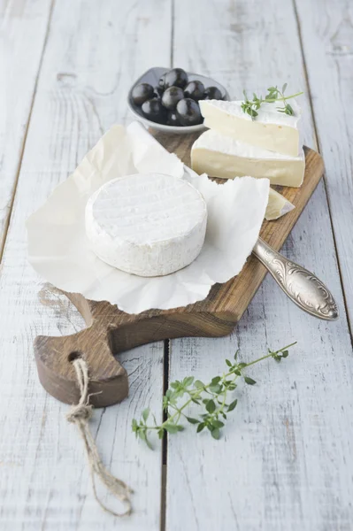 Queso Brie con galletas y aceitunas en la mesa de madera blanca —  Fotos de Stock