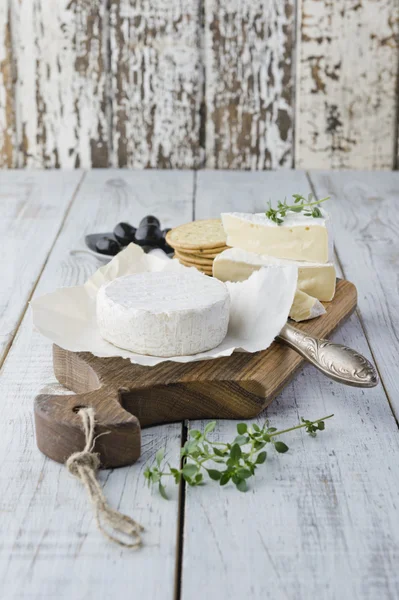 Queso Brie con galletas y aceitunas en la mesa de madera blanca —  Fotos de Stock