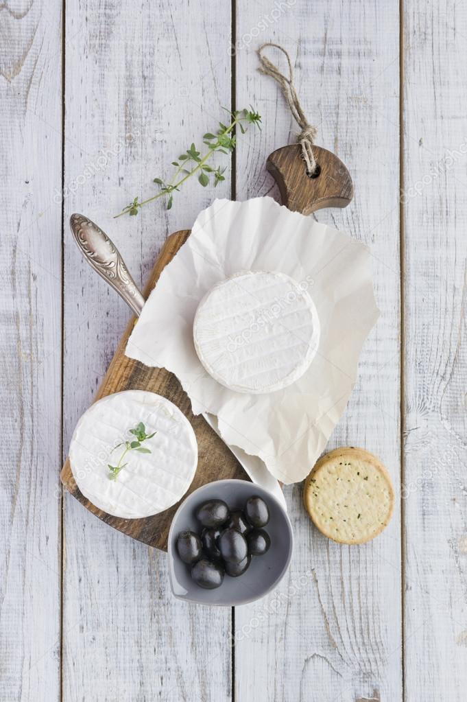 Brie cheese with crackers and olives on the white wooden table Stock