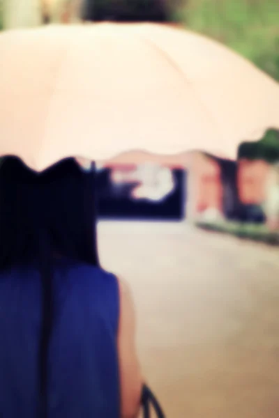 Vintage embaçado cena de costas de uma mulher com guarda-chuva rosa . — Fotografia de Stock