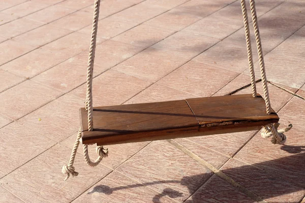 Columpio de madera colgando de un par de cuerdas en el calentamiento de la luz solar . — Foto de Stock