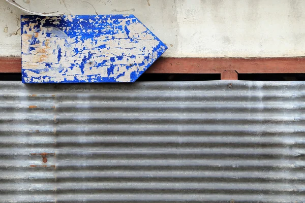 Roestige golfplaten en vuile muur met grungy blauwe pijl guid — Stockfoto