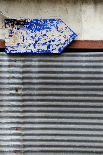 Roestige golfplaten en vuile muur met grungy blauwe pijl guid — Stockfoto