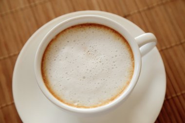 Ahşap masa üstünden gördüm üzerinde süt köpüğü ile kahve.