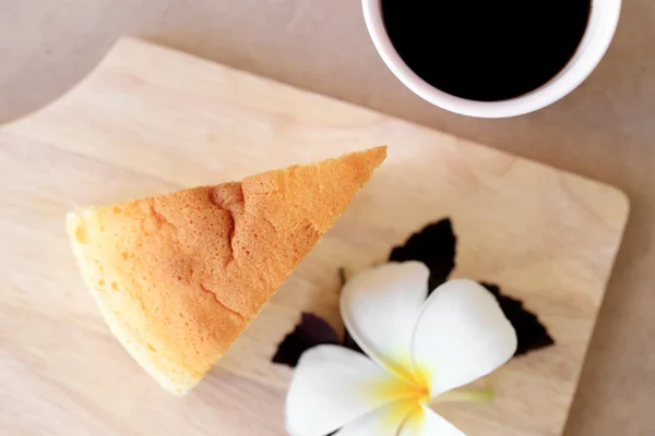 Pieces of Japanese style Cheesecake and cup of black coffee, top view on wooden plate.