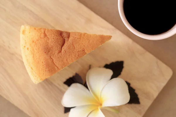 Pieces of Japanese style Cheesecake and cup of black coffee, top view on wooden plate.