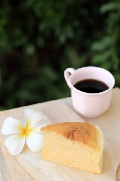 Pieces of Japanese style Cheesecake and cup of black coffee with green garden background. — Stock Photo, Image