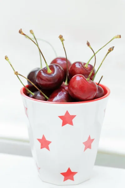 Red cherry in white ceramic cup.
