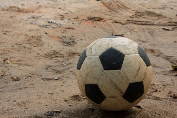 An old soccer ball on sand — Stock Photo, Image