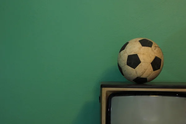 An old soccer ball on a retro TV with retro green paint wall — Stock Photo, Image