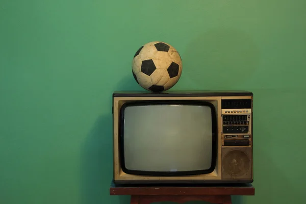 An old soccer ball on a retro TV with retro green paint wall — Stock Photo, Image