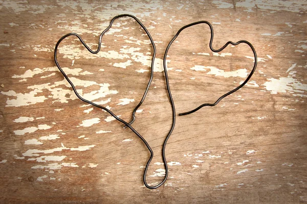 Two wire heart on wooden background
