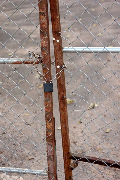 A metallic padlock and chain lock at fence door. — Stock Photo, Image