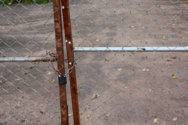 Un candado metálico y una cerradura de cadena en la puerta de la cerca . — Foto de Stock