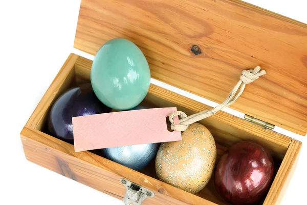 Colorful easter eggs in wood box on white background with paper — Stock Photo, Image