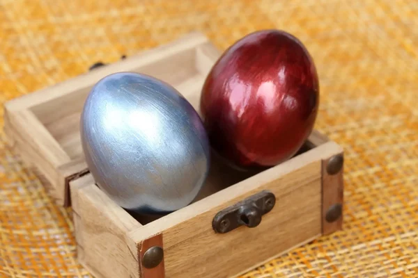 Barevné velikonoční vejce v malých truhla na bambusové tkát list backg — Stock fotografie