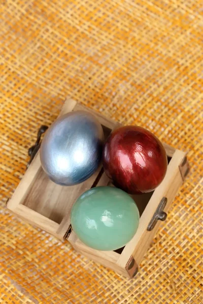 Colorful easter eggs in small wood case on bamboo weave sheet ba — Stock Photo, Image