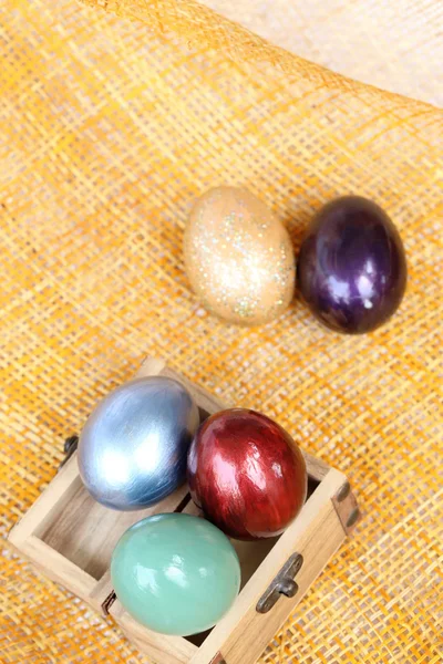 Colorful easter eggs in wood box on bamboo weave sheet. — Stock Photo, Image