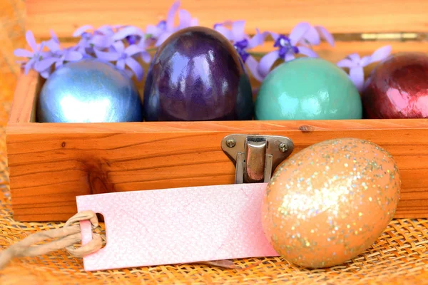 Colorful easter egg in wood box with blank paper tag. — Stock Photo, Image