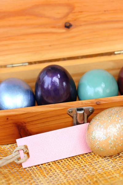 Colorful easter egg in wood box with paper tag. — Stock Photo, Image