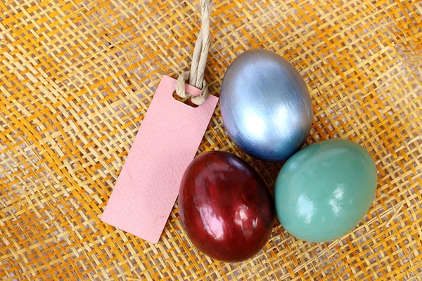 Colorful easter egg on bamboo weave background with paper tag. — Stock Photo, Image
