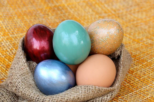Colorful easter eggs in burlap hessian sacking bag. — Stock Photo, Image