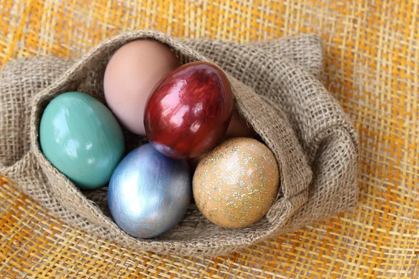 Colorful easter eggs in burlap hessian sacking bag. — Stock Photo, Image