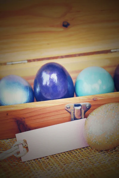 Ahşap kutusunda kağıt etiket, vintage tarzı pr ile renkli Paskalya yortusu yumurta — Stok fotoğraf