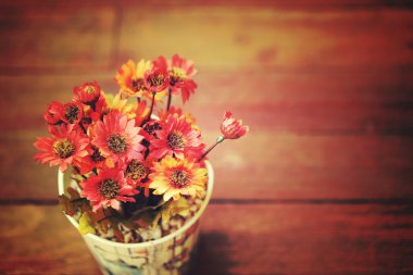 Boş alanı olan ahşap masa üzerinde küçük tencerede yapay çiçekler